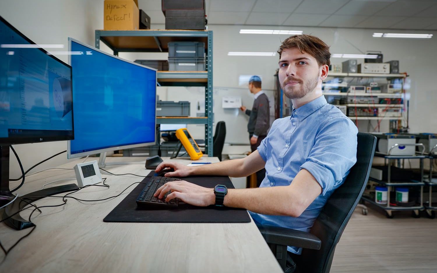 Jaron van der Velden achter twee monitors in een technisch lab